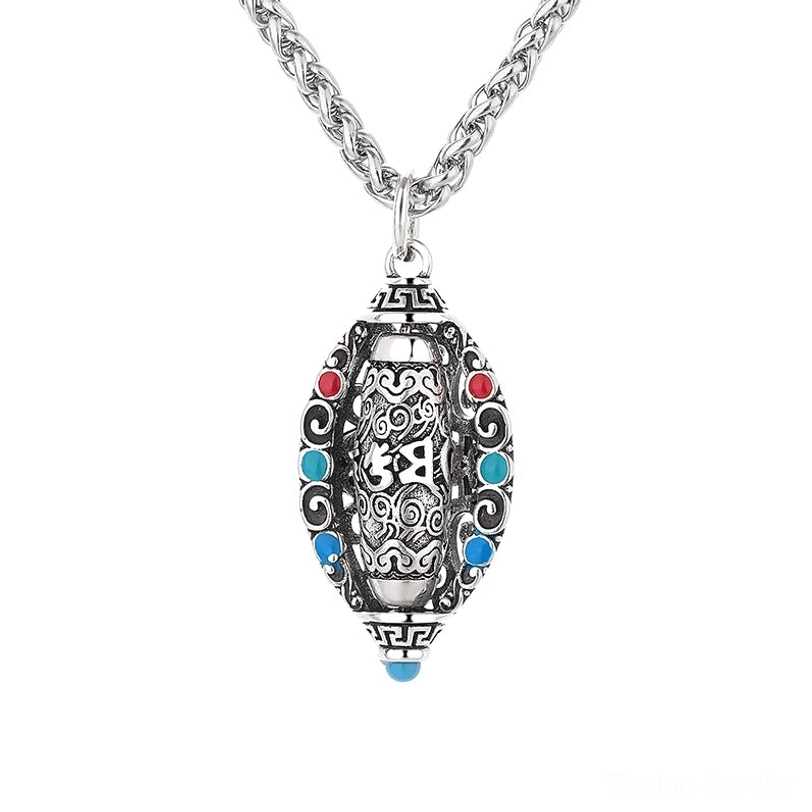 Rotatable Tibetan mantra pendant close-up with different carved Buddhist symbols on rotating sections, retro silver texture and edge gem details