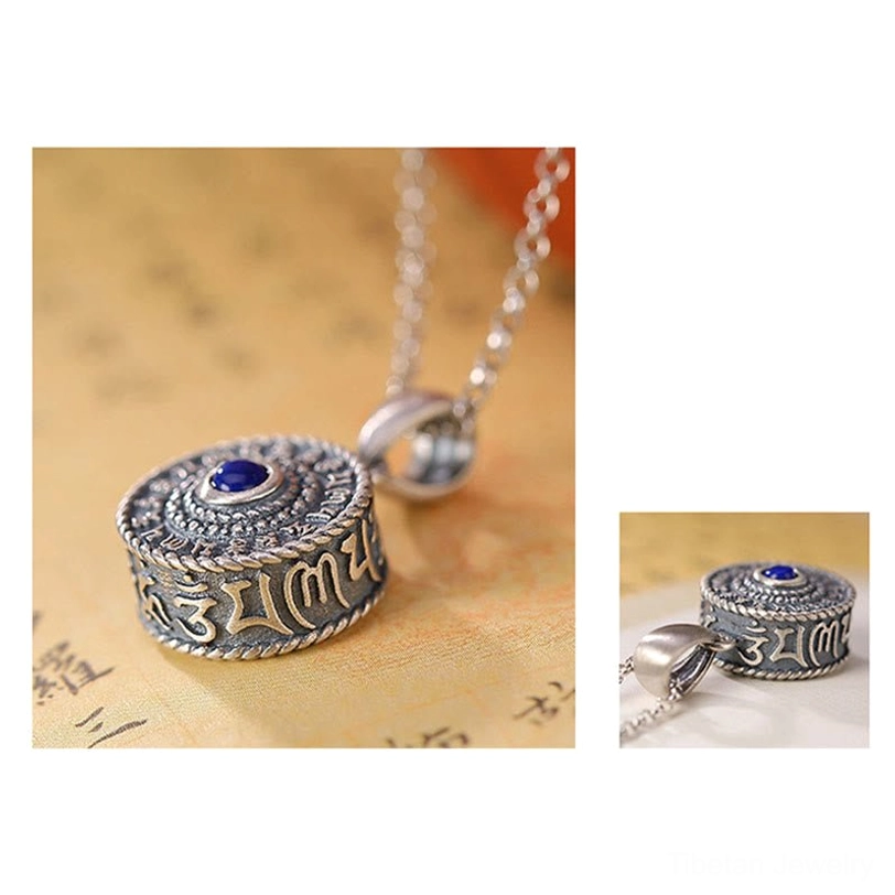 Low side view of handcrafted Om Mani Padme Hum 925 Sterling Silver pendant on Buddhist scripture background, displaying visible Sanskrit mantras around cylinder and lapis stone top