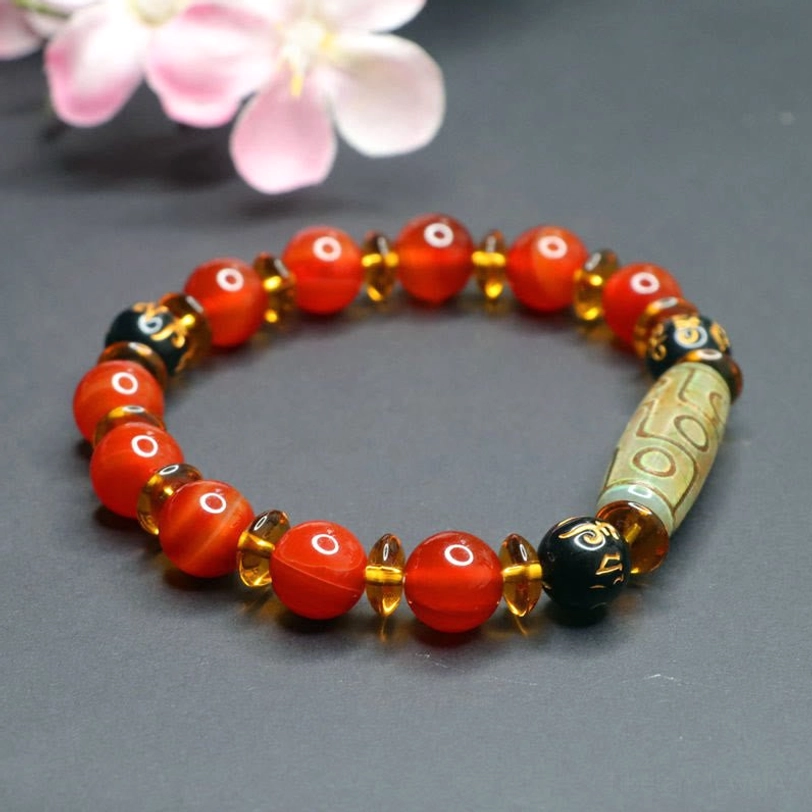 Six true words om mani padme hum red agate bracelet circular layout with gold-toned metal spacers, displayed against pink cherry blossom background