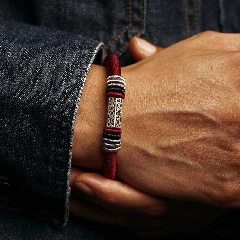 Red Om Mani Padme Hum blessed bracelet worn on male wrist with denim clothing