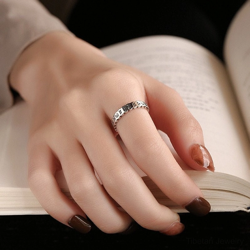 Mantra ring worn on hand with neutral nail art, om mani padme hum ring on index finger during meditation or reading