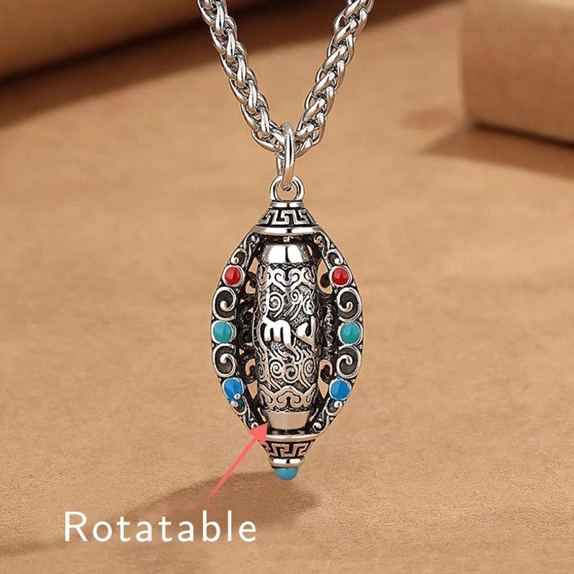 Tibetan Om Mani Padme Hum rotatable copper necklace pendant front view with carved Buddhist patterns and colored gemstone inlays on kraft paper