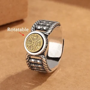 Om Mani Padme Hum rotatable copper ring with gold central disc carved with Tibetan mantra, showing twisted silver band and engraved sutra patterns from front-left angled view