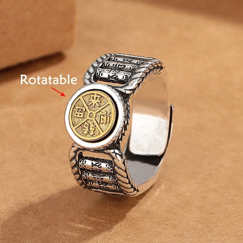 Om Mani Padme Hum rotatable copper ring with gold central disc carved with Tibetan mantra, showing twisted silver band and engraved sutra patterns from front-left angled view
