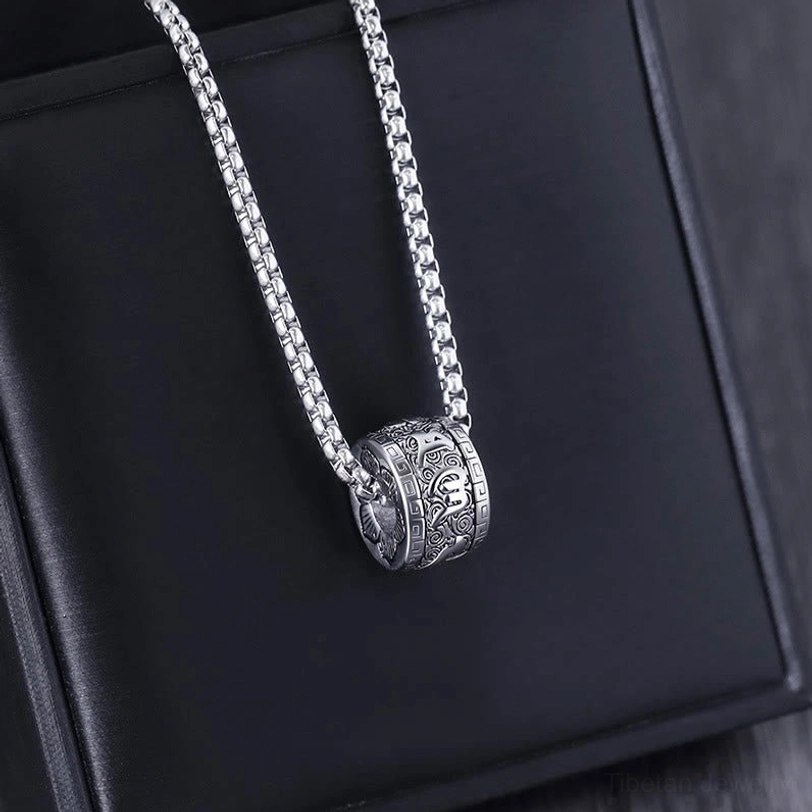 Om Mani Padme Hum all-silver mantra necklace with engraved barrel pendant displayed at angled side view on black leather surface