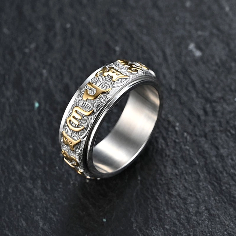 Om Mani Padme Hum two-tone titanium steel spinner ring with silver and gold finish, side view showing carved sacred mantra patterns
