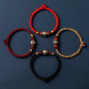 Flat lay collection of multiple Om Mani Padme Hum Tibetan bracelets in different colors (red, black, multicolored) with silver mantras