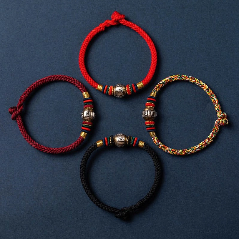 Flat lay collection of multiple Om Mani Padme Hum Tibetan bracelets in different colors (red, black, multicolored) with silver mantras