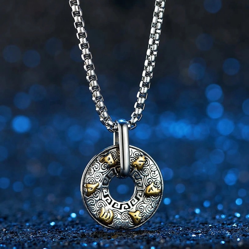 Om Mani Padme Hum necklace with vintage silver base and gold tibetan mantra studs on square box chain against blue bokeh background