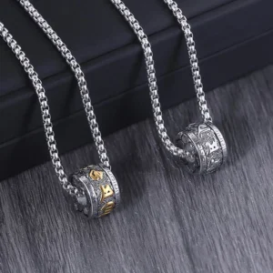Twin Om Mani Padme Hum mantra necklaces with engraved silver barrel pendants displayed on black presentation box with wooden table background