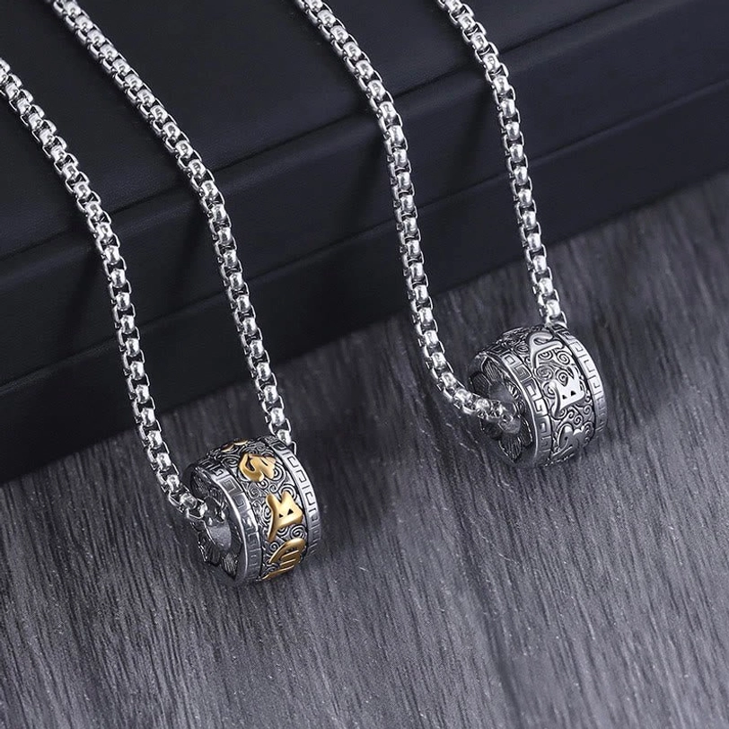 Twin Om Mani Padme Hum mantra necklaces with engraved silver barrel pendants displayed on black presentation box with wooden table background