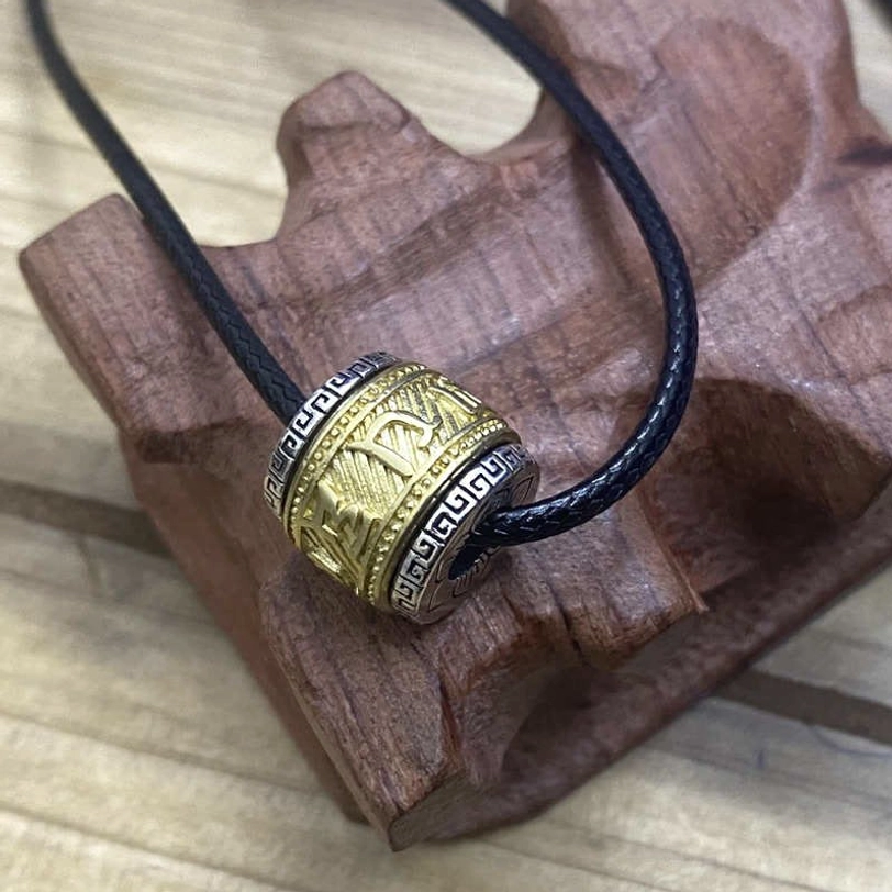 Two-tone Tibetan mantra pendant with gold and silver mixed metal, black wax cord, featuring engraved Buddhist text and symbols