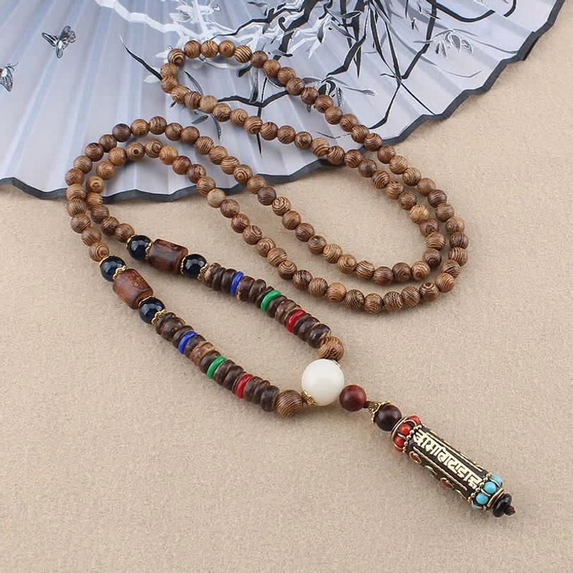 Om Mani Padme Hum wenge wood bead necklace with enamel mantra pendant and colored spacer beads, overhead view