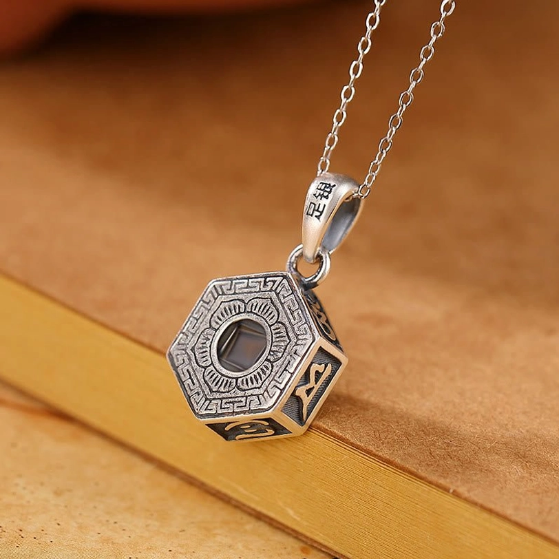 Sacred Om Mani Padme Hum projection pendant overhead view showing bail marked 925 sterling silver and bagua pattern design on vintage stationery backdrop