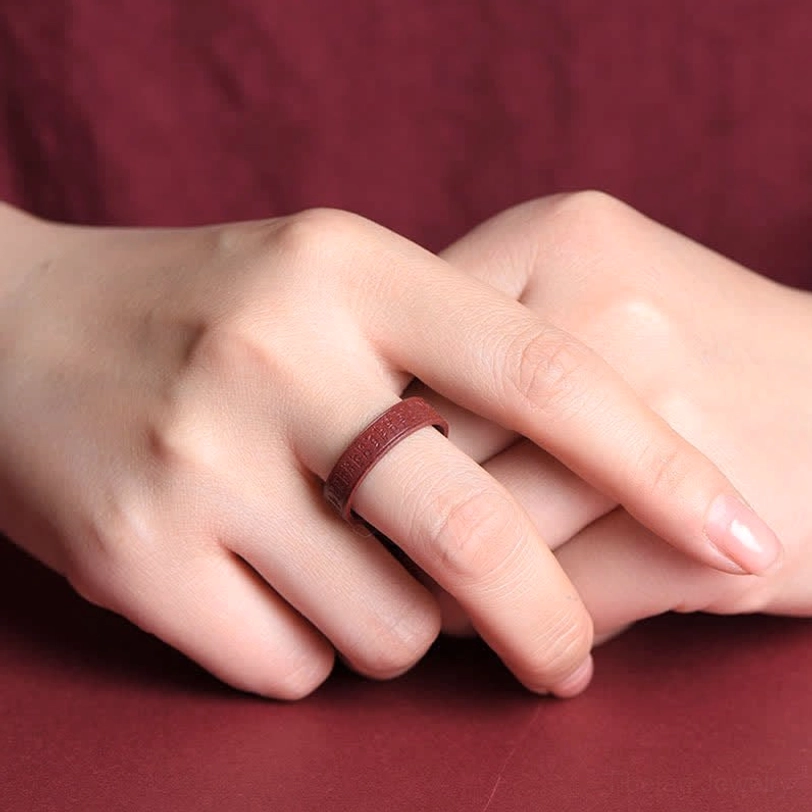 Om mani padme hum engraved cinnabar ring worn on finger showing mantra carving and natural hand positioning