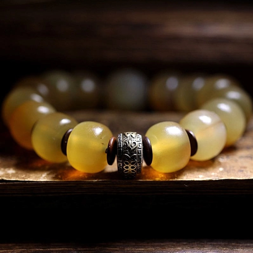 Om Mani Padme Hum sheep horn bracelet featuring central carved metal spacer and glossy natural beads