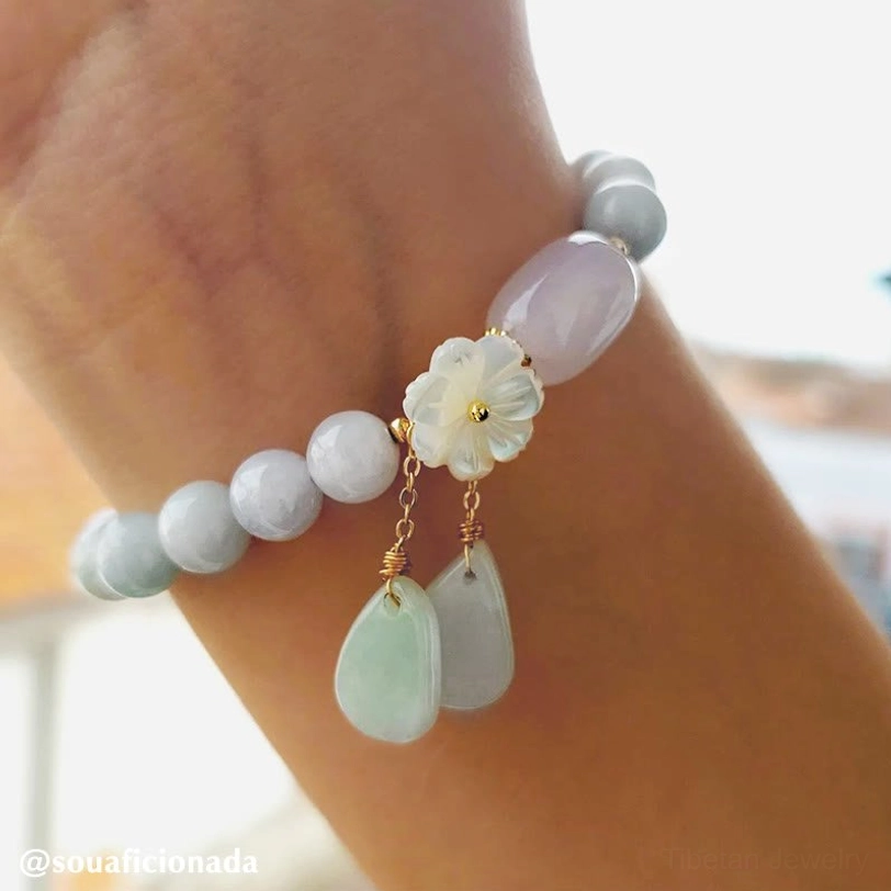 Gradient pale tone jade beaded bracelet with gold chain pendants and shell flower charm on wrist