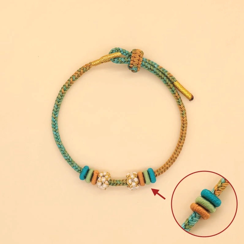 Peach blossom knot braided bracelet in teal and amber colors with enlarged knot detail close-up