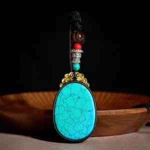 Peacock green ebony wood oval tribal necklace pendant with black veining, front view on wooden tray