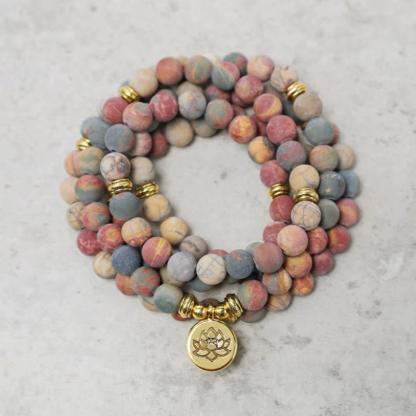 Picasso jasper mala bead bracelet with lotus charm pendant close-up flat lay