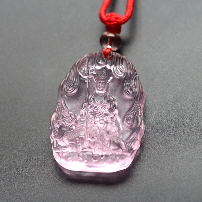 Light pink-purple Ksitigarbha Buddha Liuli crystal pendant with flame carved border, seated Bodhisattva holding staff, red braided cord with red bead accent
