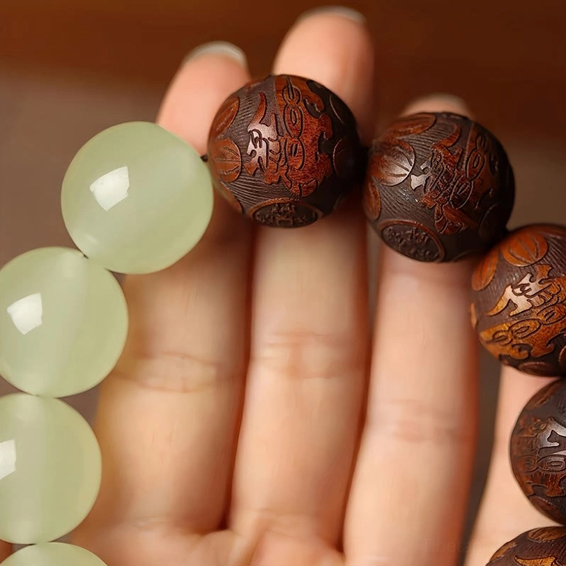 Macro detail of bracelet beads showing polished jade and intricately carved wooden Pixiu patterns