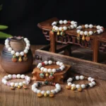 Gold Pixiu family charm bracelets collection displaying multiple colorful liuli glass bead styles with enamel pendants on wooden vintage decor