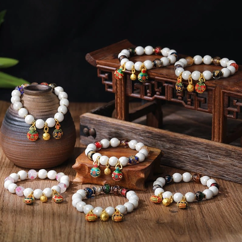 Gold Pixiu family charm bracelets collection displaying multiple colorful liuli glass bead styles with enamel pendants on wooden vintage decor