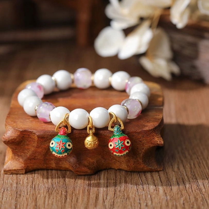 Pink love heart Pixiu charm bracelet with gradient porcelain beads and enamel heart pendant on wooden display stand with floral background