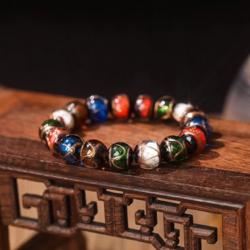 Single Five Elements Gold Pixiu Family Charm Liuli glass bead bracelet close-up side view on carved wooden surface, polished mixed-color glass beads without hanging charms