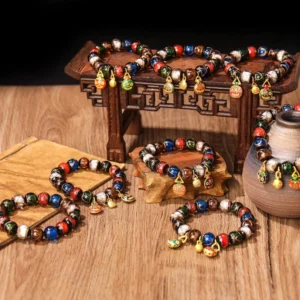 Assorted Five Elements Gold Pixiu Family Charm bracelets with diverse colored Liuli glass beads and matching gold enamel charms on wooden table, flat overhead view
