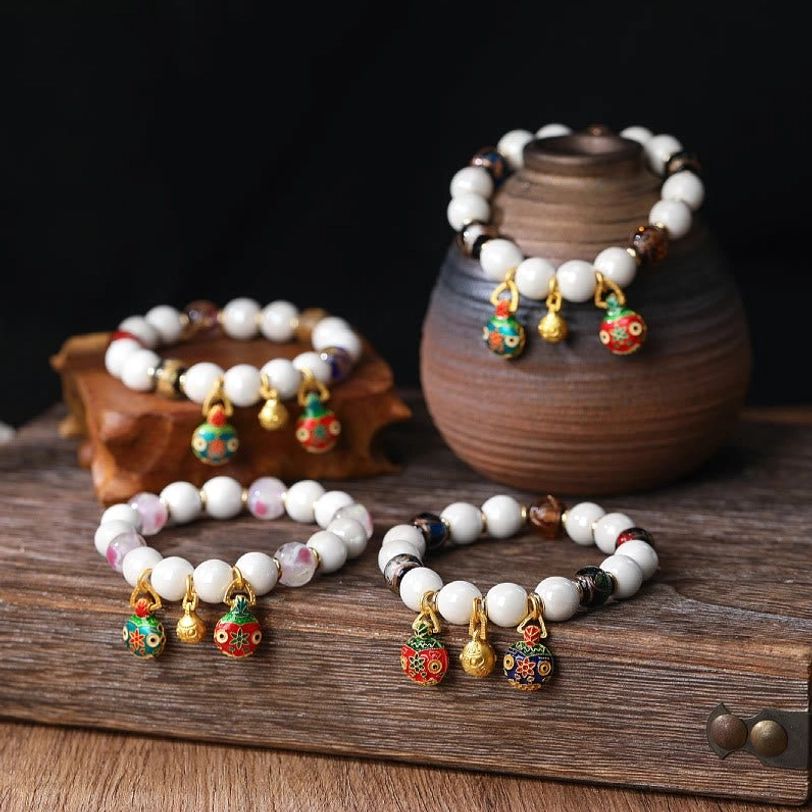 Festive Gold Pixiu charm bracelets featuring warm white red and gold tones with enamel fish-shaped hanging pendants on wooden tray display