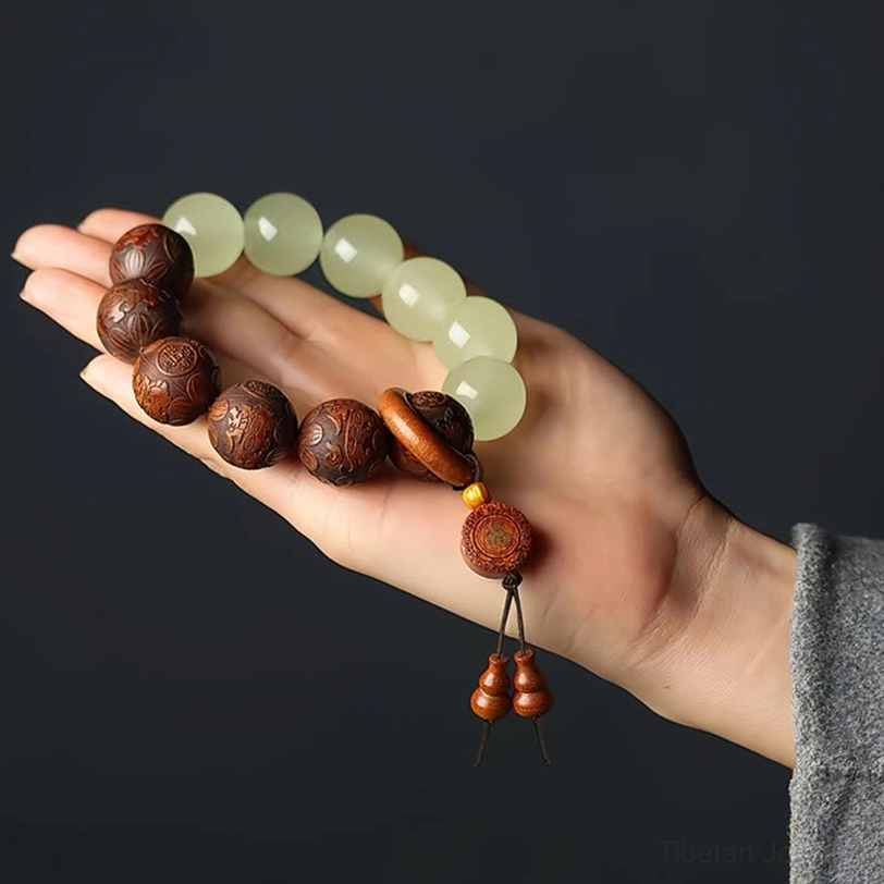 Palm held dual material beaded bracelet showing engraved Pixiu wood beads and smooth glowstone jade