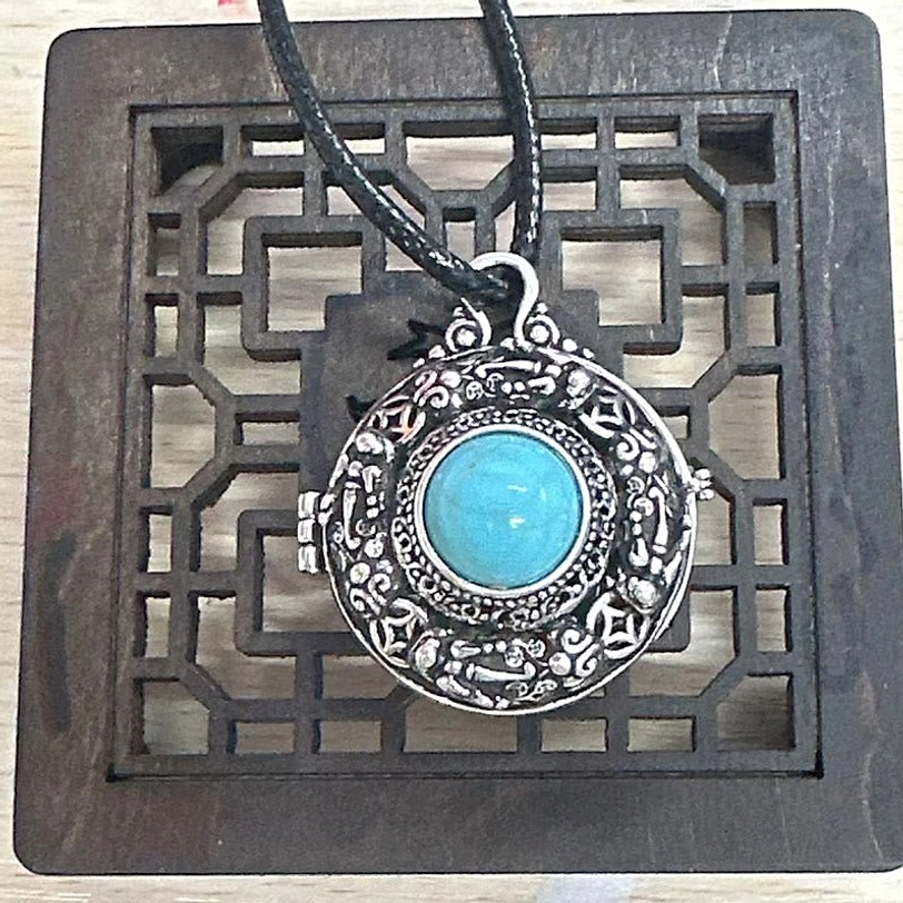Tibetan Pi Xiu necklace with black leather cord - vintage copper pendant with turquoise center on bohemian background
