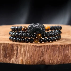 Hand-carved Pixiu black obsidian beaded bracelet with rainbow luster and tiger stone accents flat lay display