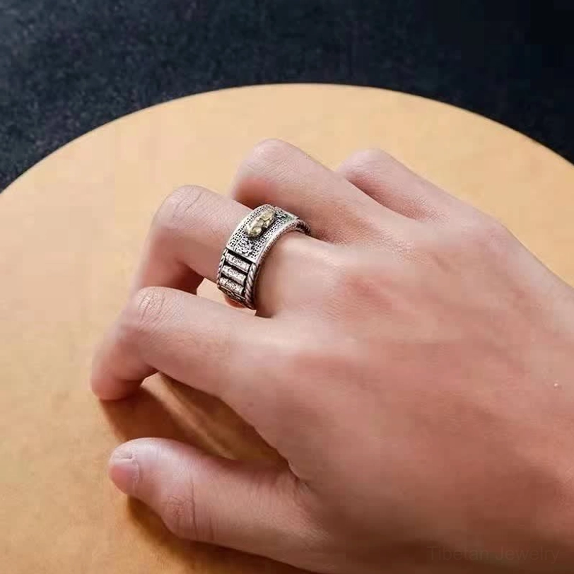 Pixiu prayer wheel ring worn on hand showing retro silver finish with carved band details on wooden surface