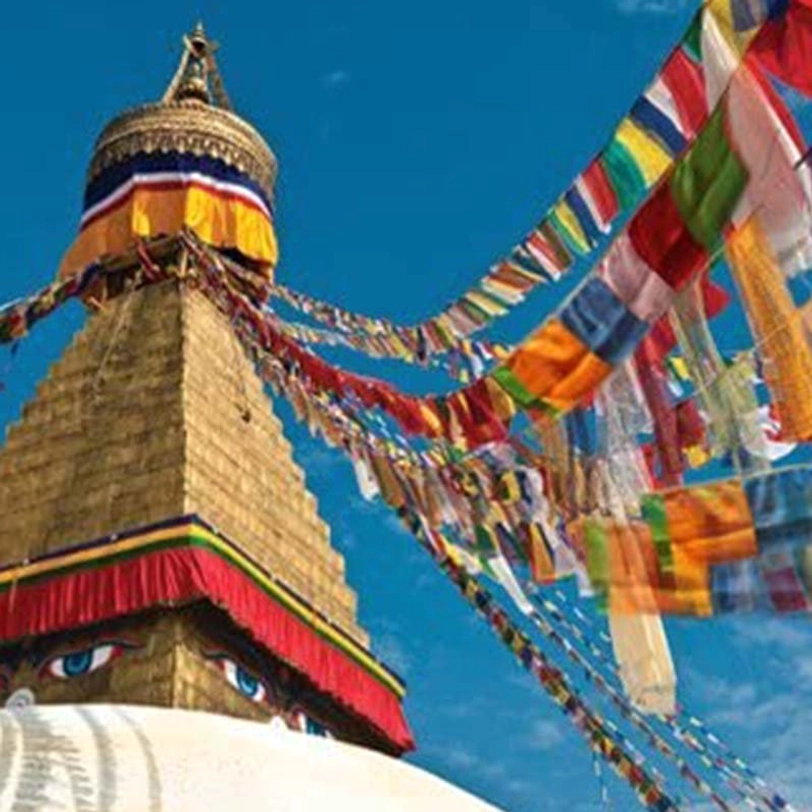 Colorful prayer flags fluttering at Buddhist stupa with blue sky traditional temple architecture