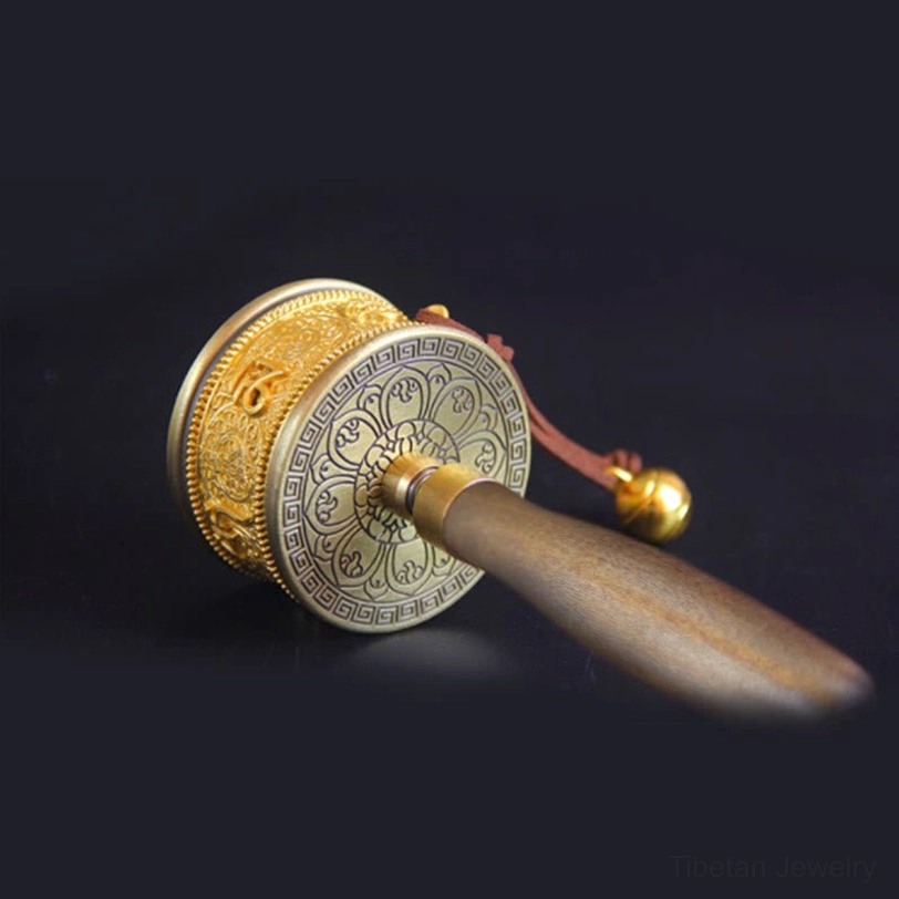 Right side view of handmade copper prayer wheel featuring floral patterned end cover, natural wooden handle, and brass decorative bell