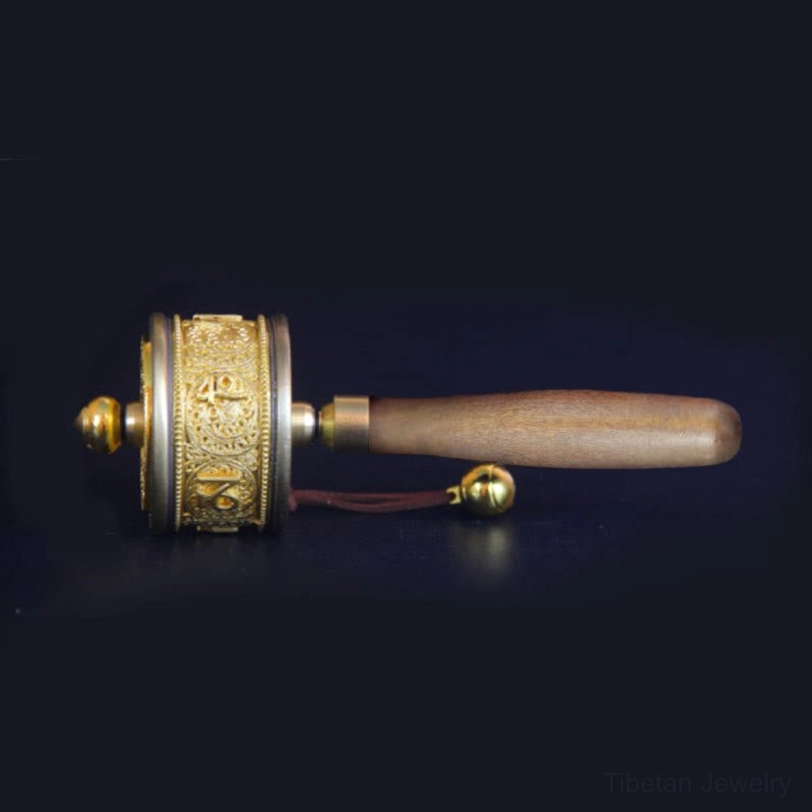 Flat side view of handcrafted Tibetan prayer wheel showing short hanging strap, small brass bell, and smooth ergonomic wooden handle