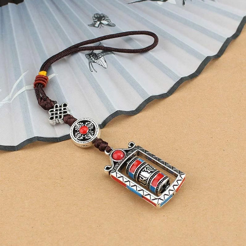 Tibetan Om Mani Padme Hum keychain with red blue accents, Chinese knot charm detail, displayed with traditional fan prop
