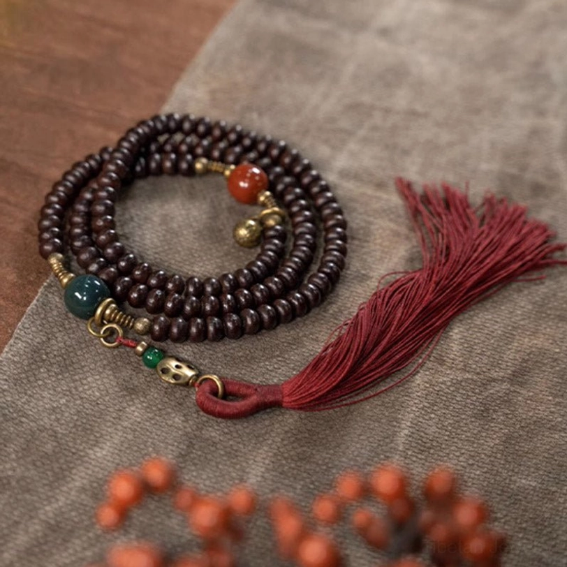 Multi-loop purple bodhi seed mala bracelet displayed on natural linen fabric