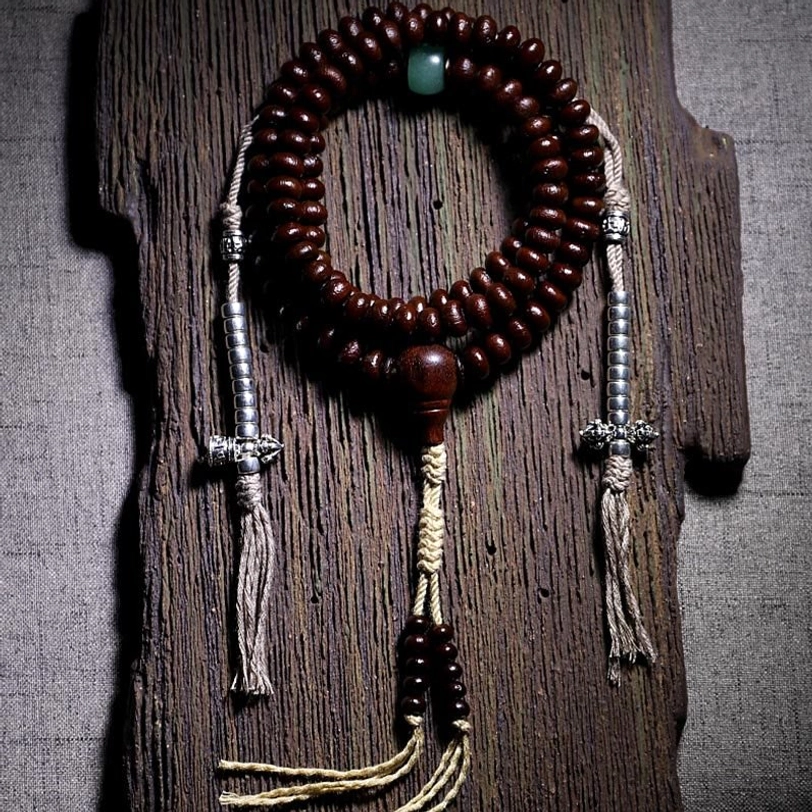 Tibetan mala with purple bodhi seeds and copper dorje counters on traditional background