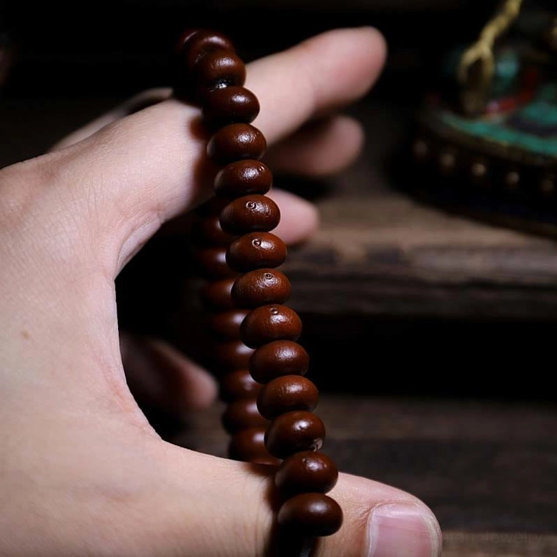 Close-up of purple bodhi seed beads held in hand showing smooth natural texture and craftsmanship