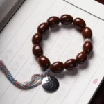 Purple gold rat wealth bracelet with OM charm and Bagua symbol, flat lay display on Chinese calligraphy paper background