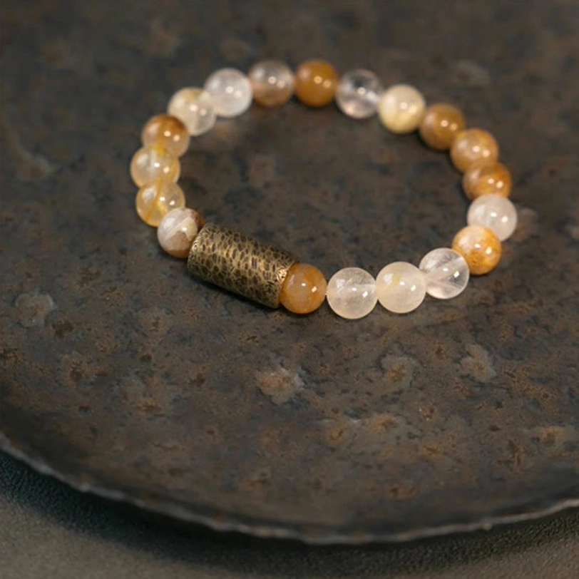 Love and wisdom crystal bracelet with purple phantom quartz beads, flat lay on neutral background