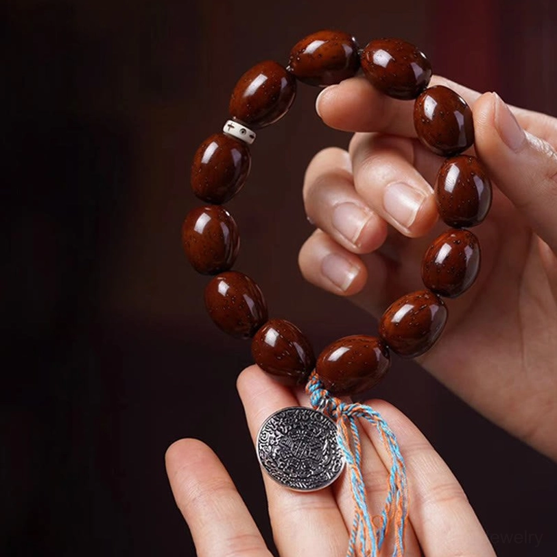 Purple gold rat charm bracelet held in two hands, demonstrating comfort fit and natural bead texture with tasseled metal pendant