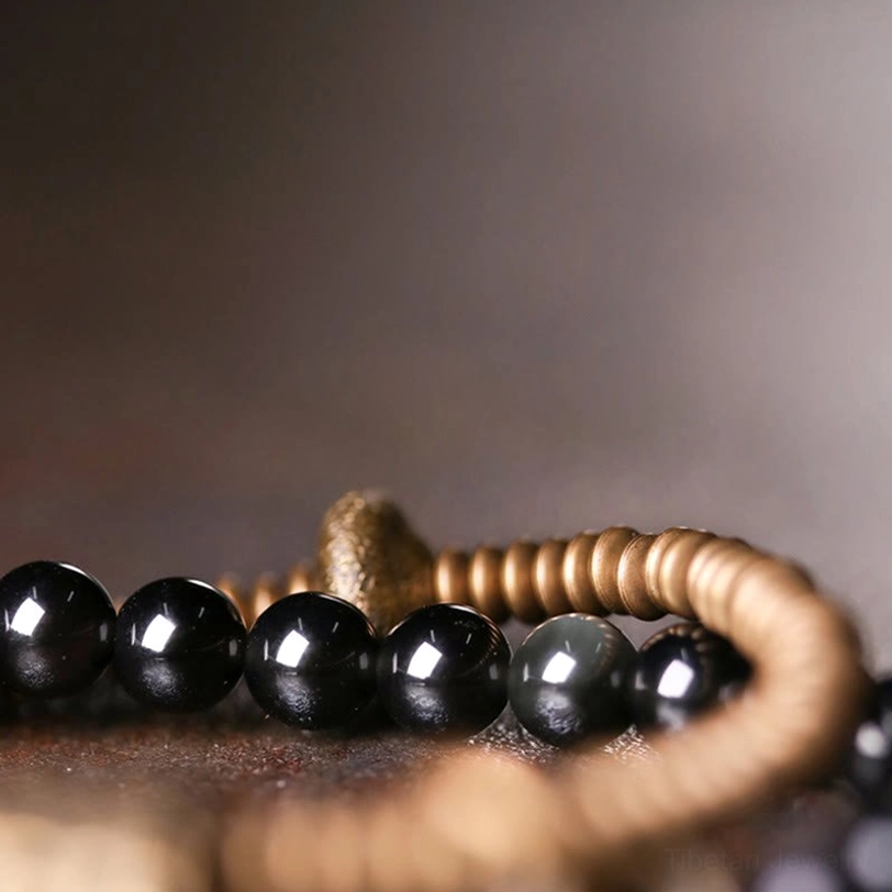 Close-up macro view of iridescent rainbow obsidian beads strung with bronze coil elements, showing gemstone detail and metalwork