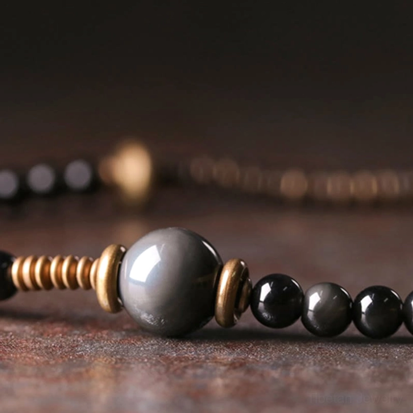 Rainbow obsidian multilayer bracelet section detail with gray glossy beads and coiled antique bronze metal spacers