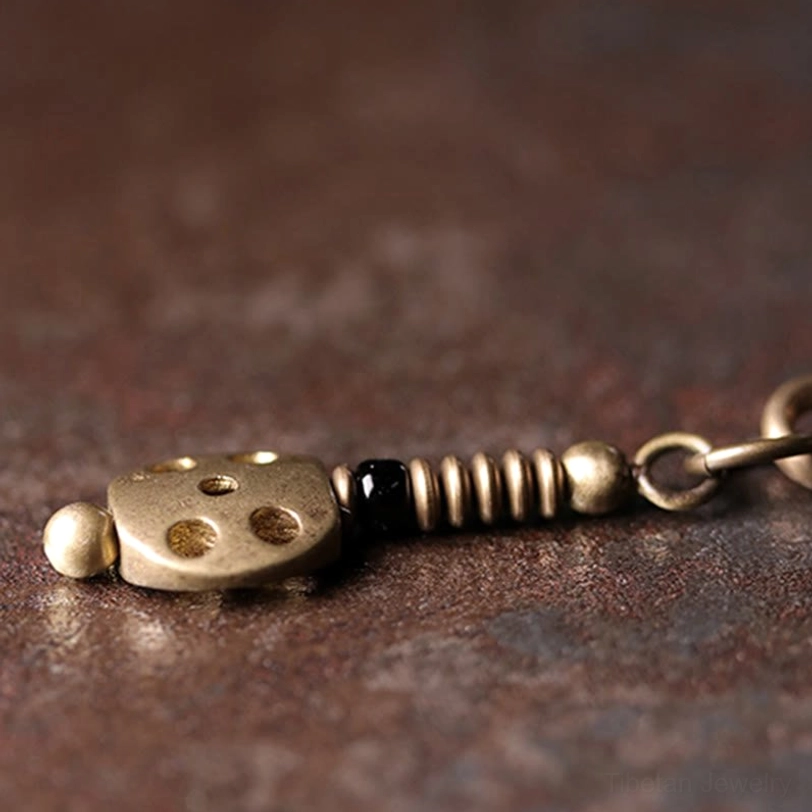 Rainbow obsidian bracelet clasp detail with dice-shaped bronze pendant and elastic spring mechanism