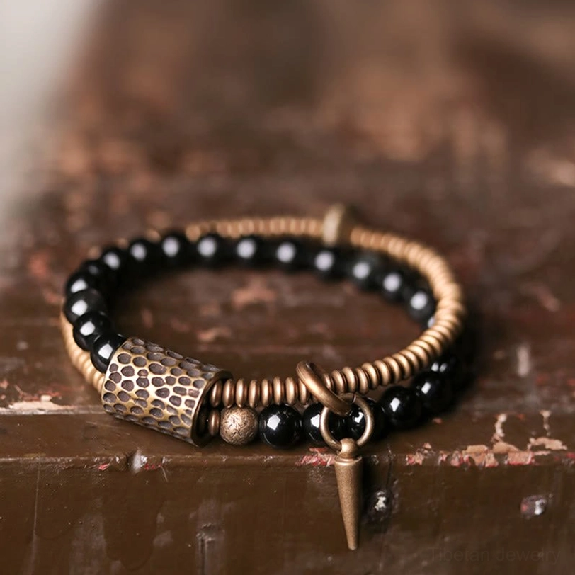 Close-up detail of double layered rainbow obsidian bracelet showing hammered bronze tube beads, bronze spacers, and polished obsidian stones